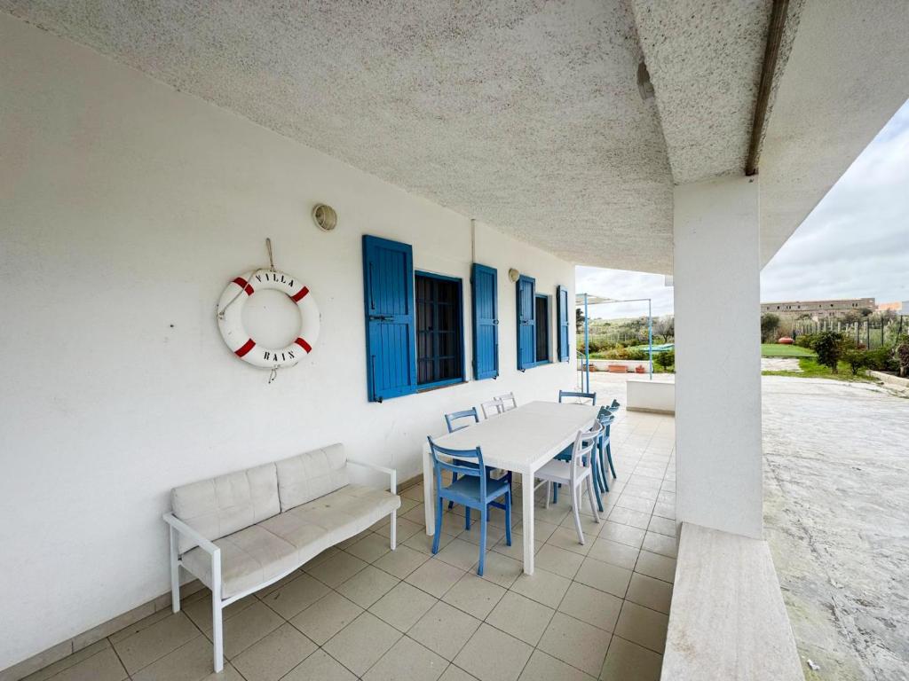 d'une terrasse avec une table, des chaises et une horloge. dans l'établissement Villa Marzamemi with pool, à Marzamemi
