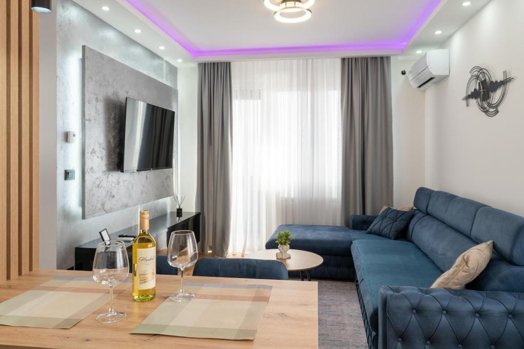 a living room with a blue couch and a table with wine glasses at Apartman 51 Sarajevo in Donje Mladice