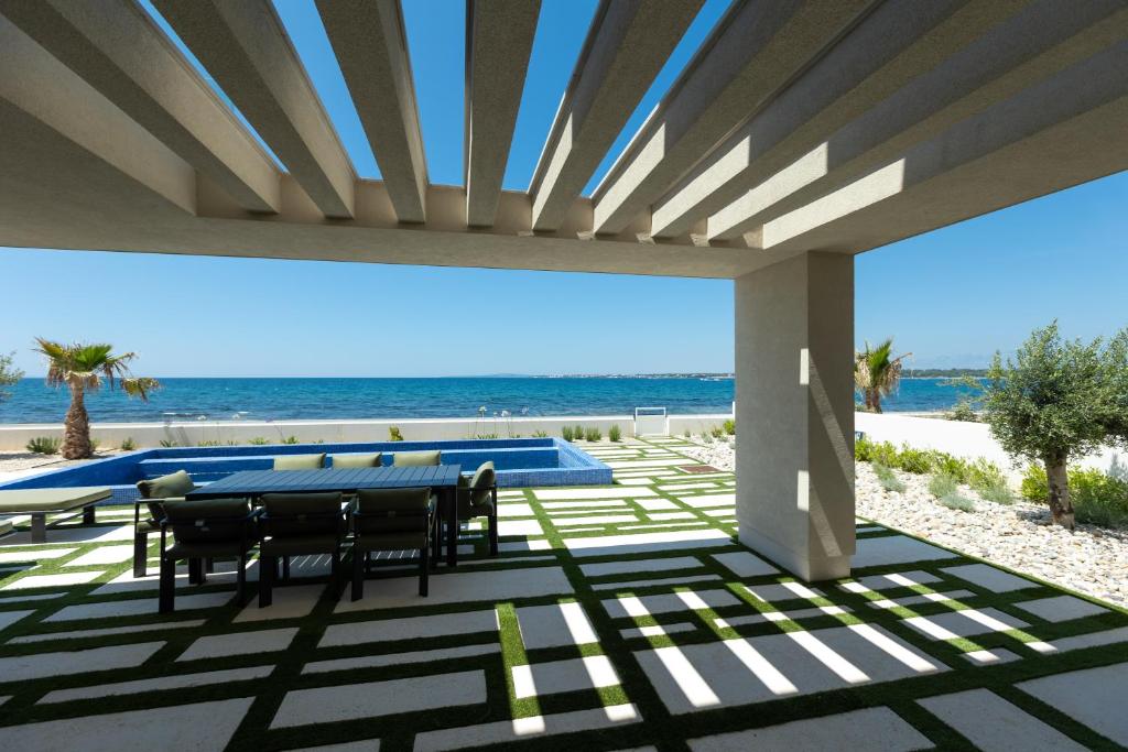 a patio with a table and chairs and the beach at Adria Resort SEAFRONT Villa C Private Pool Pet Friendly in Zaton
