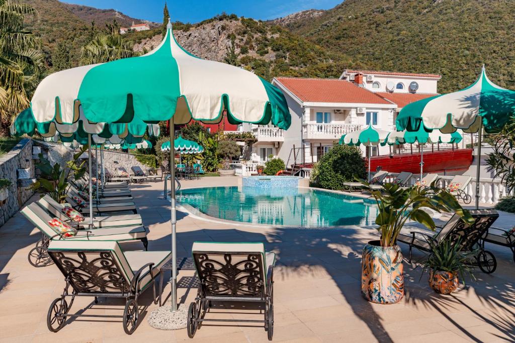 una piscina in un resort con sedie e ombrelloni di Monte Aria panorama suites a Herceg-Novi