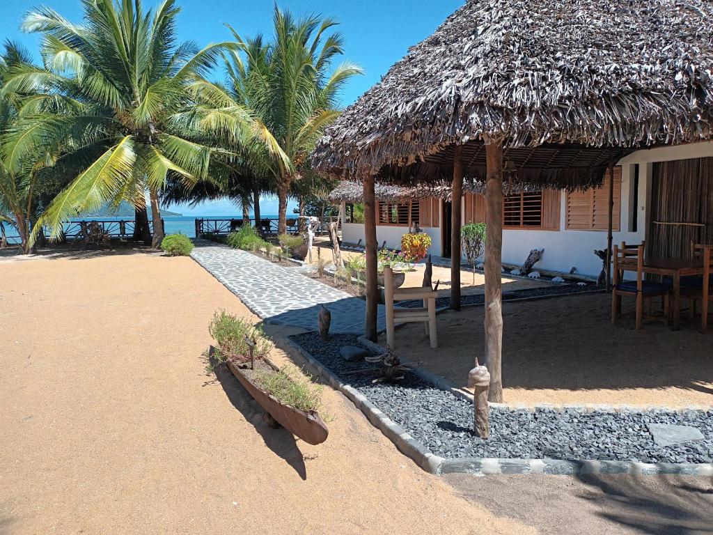 a hut with a table and a fire hydrant on a beach at Ravoravo Beachfront Family lodge in Lokobe National Park-Nosy be, autentic Madagascar expiriance with europian confort in Antafondro