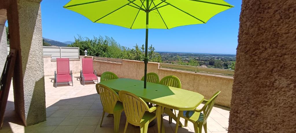 a green table with chairs and an umbrella on a balcony at Entre mer et montagne in Monte