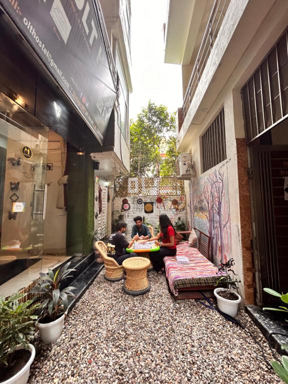 twee mensen zitten op een bank in een binnenplaats bij OLT Hostel Rishikesh in Rishīkesh