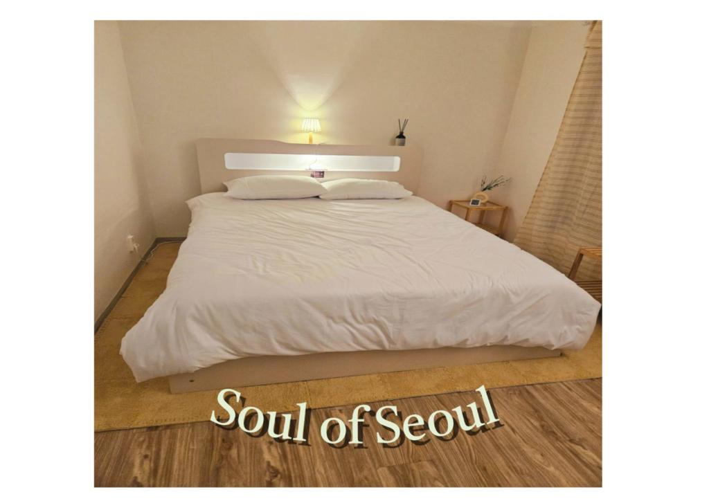 ein Bett mit weißen Laken und Kissen in einem Schlafzimmer in der Unterkunft Soul of Seoul - Cozy 3 room stay, 3min from SNU Station in Seoul