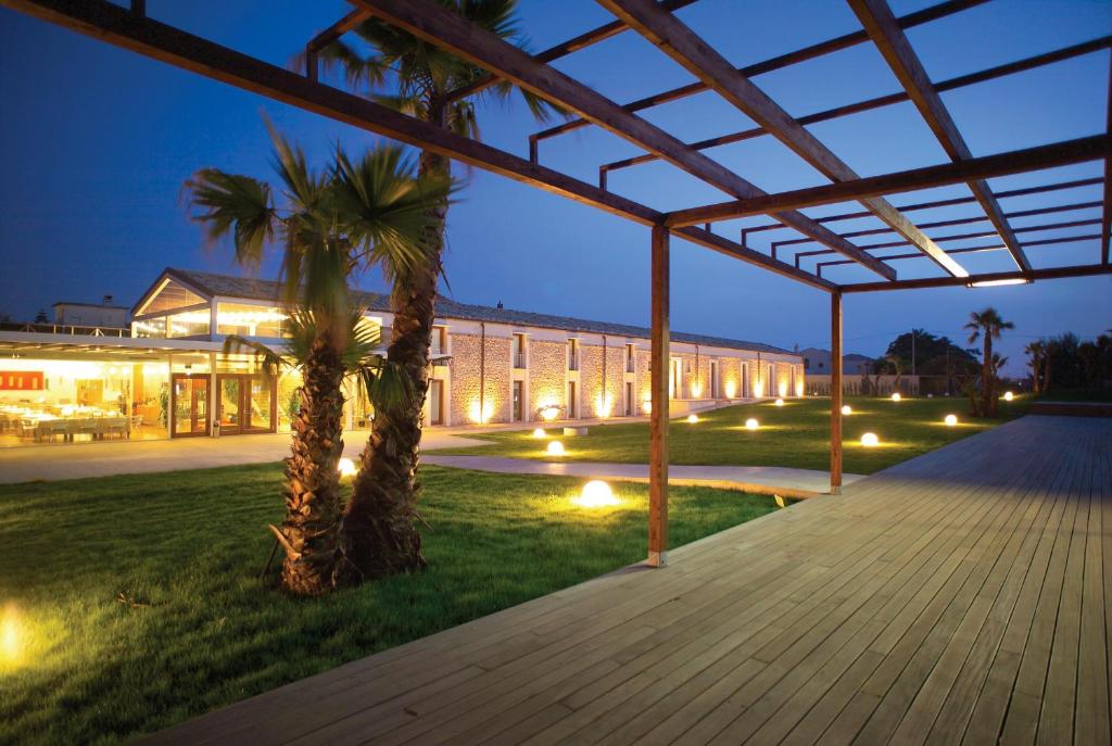 a large building with palm trees in front of it at Aura Club - Villa Carlotta in Ragusa
