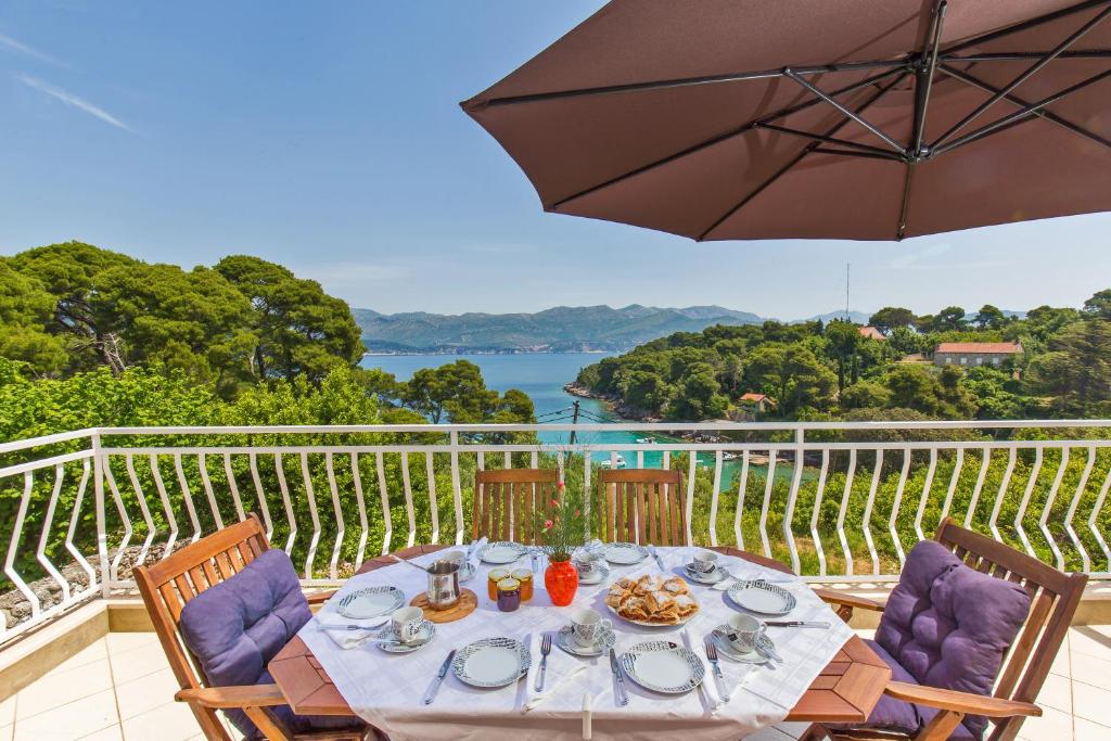 a table with food and an umbrella on a balcony at Apartment Lujak in Koločep