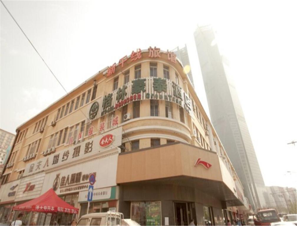 duży budynek w mieście z samochodami na ulicy w obiekcie GreenTree Inn Liaoning Dalian Railway Station South Shengli Square Express Hotel w mieście Dalian