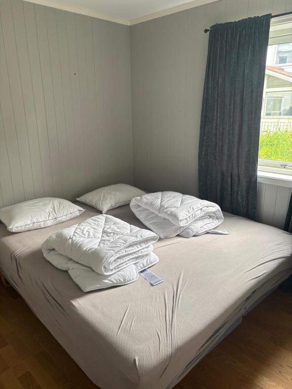 un letto con lenzuola e cuscini bianchi e una finestra di Kroken3 the apartment a Gravdal