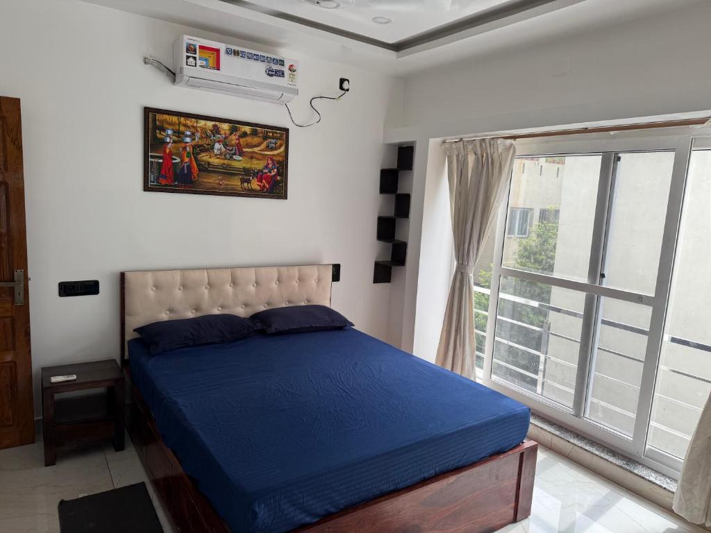 Un dormitorio con una cama azul y una ventana. en Modern, Stylish & Luxurious 1 BHK stay,22, en Bhubaneshwar