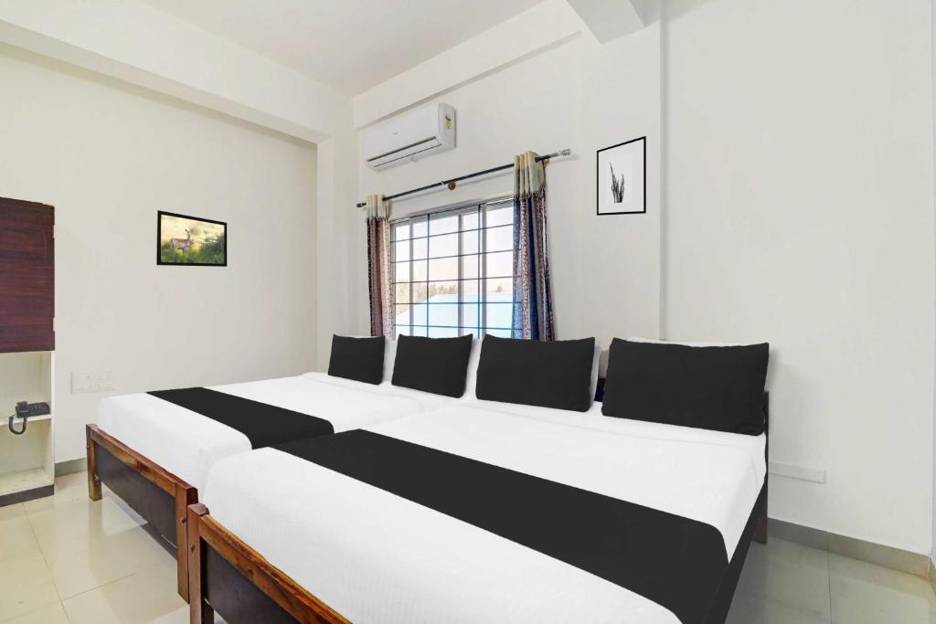 Un dormitorio con una gran cama blanca y negra. en Super Hotel O Chikmangaluru Near Railway Station, en Chikmagalur