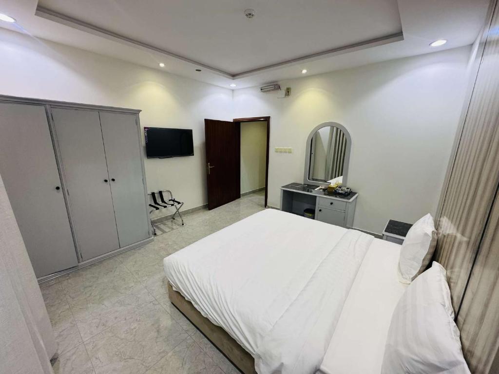 a bedroom with a white bed and a tv at شقق درة الغيم للشقق المخدومة in Taif