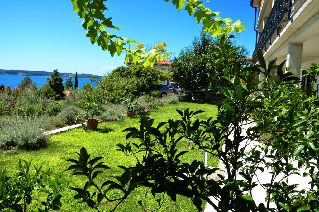 a yard with green grass and trees and a house at Apartments Ostanek 2 in Portorož