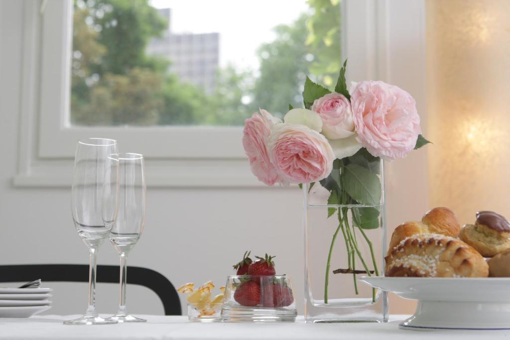 une table avec un vase de fleurs et de verres roses dans l'établissement Les Suites de Catherine, la Si Calme, à Nancy