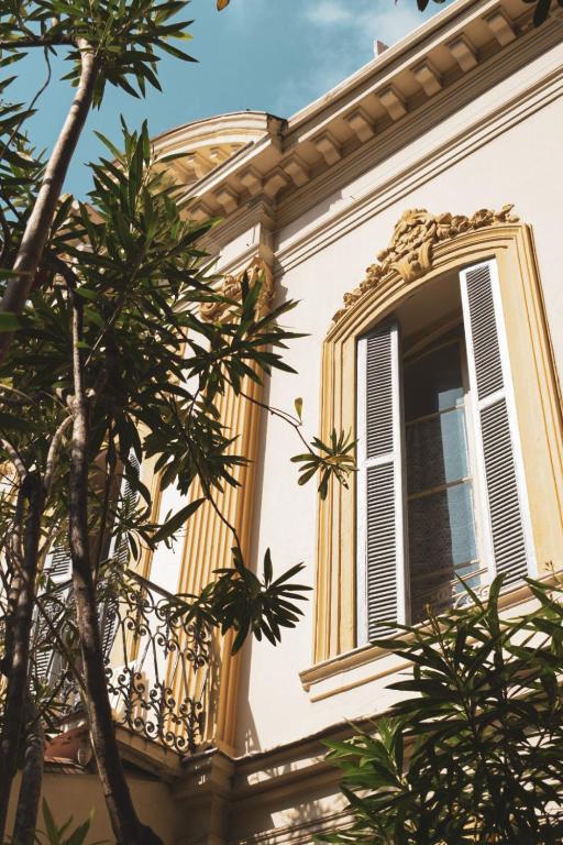 une fenêtre ouverte sur un bâtiment avec un arbre dans l'établissement Hôtel Belle Meunière, à Nice