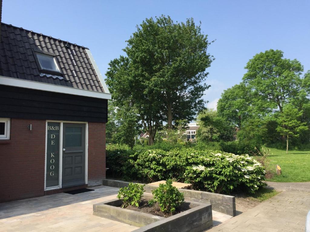 ein Haus mit einer schwarzen Tür und ein paar Büschen in der Unterkunft Appartement - B&B de Koog in Uitgeest