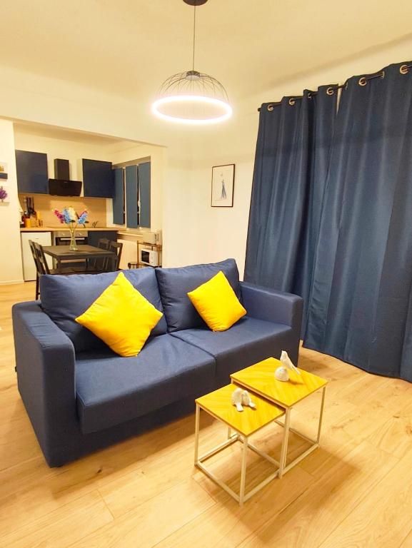 a blue couch with yellow pillows in a living room at Les suites frontalières T2 avec parking et balcon secteur Thionville Luxembourg in Basse-Yutz