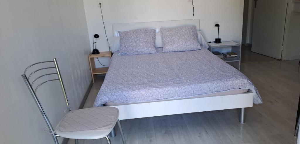 a bedroom with a white bed and a chair at Ecolieu La pépinière in Carnoux