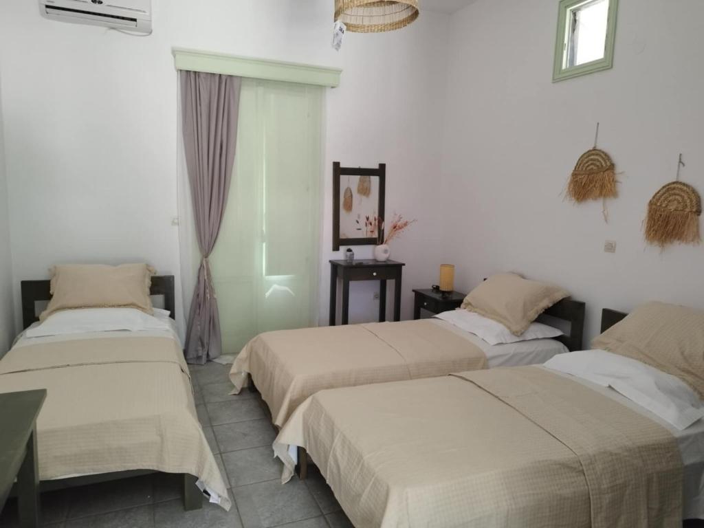 three beds in a room with white walls at Marathos in Kanakis