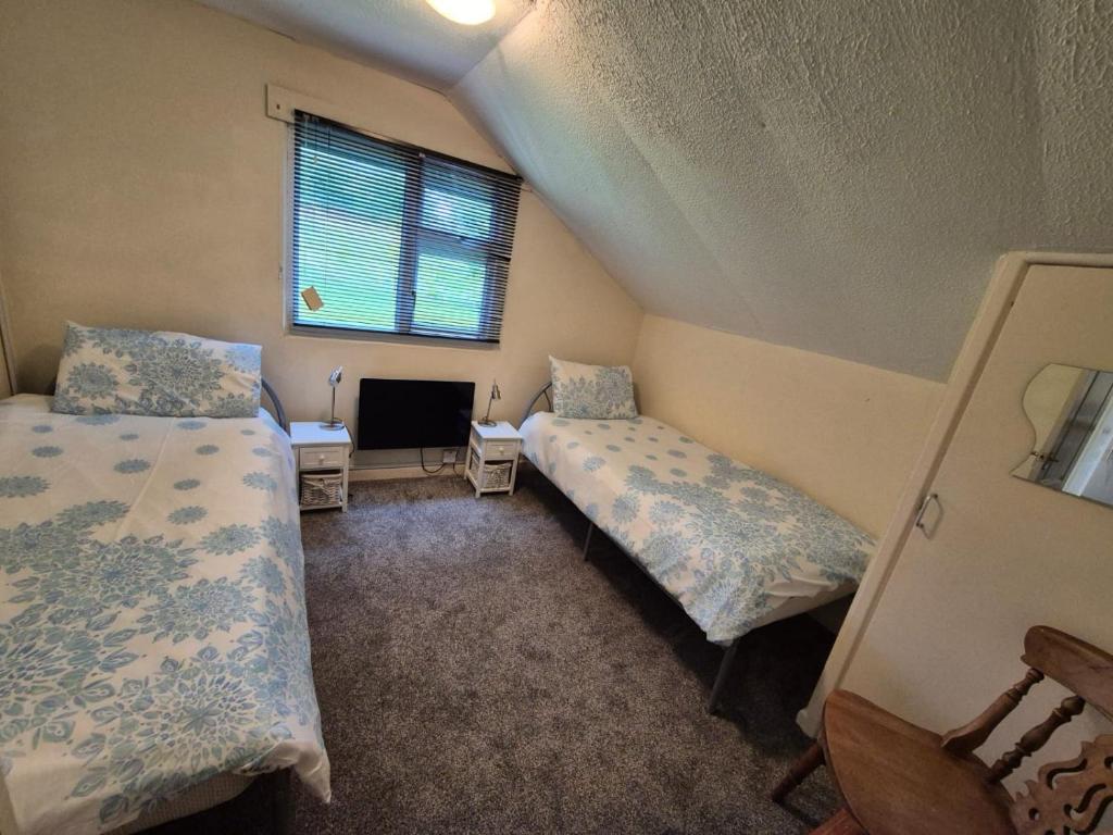 Un dormitorio abuhardillado con dos camas y una ventana. en 8 The Coombe, en Kilkhampton