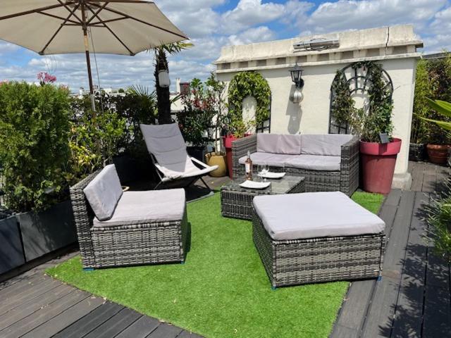 une terrasse avec des chaises en osier et un parasol dans l'établissement DERNIER ETAGE TERRASSE Pte St Coud, à Boulogne-Billancourt