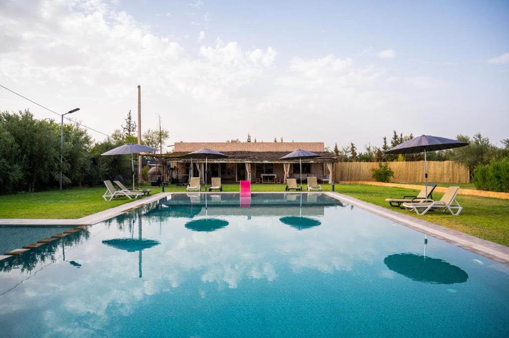 a swimming pool with blue water in front of a house at Oléa villa & lodge in Marrakesh