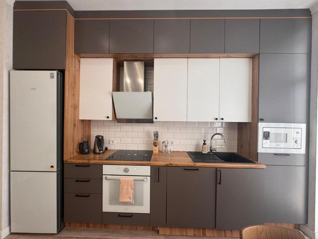 a kitchen with gray cabinets and white appliances at Altin Residens in Karagandy