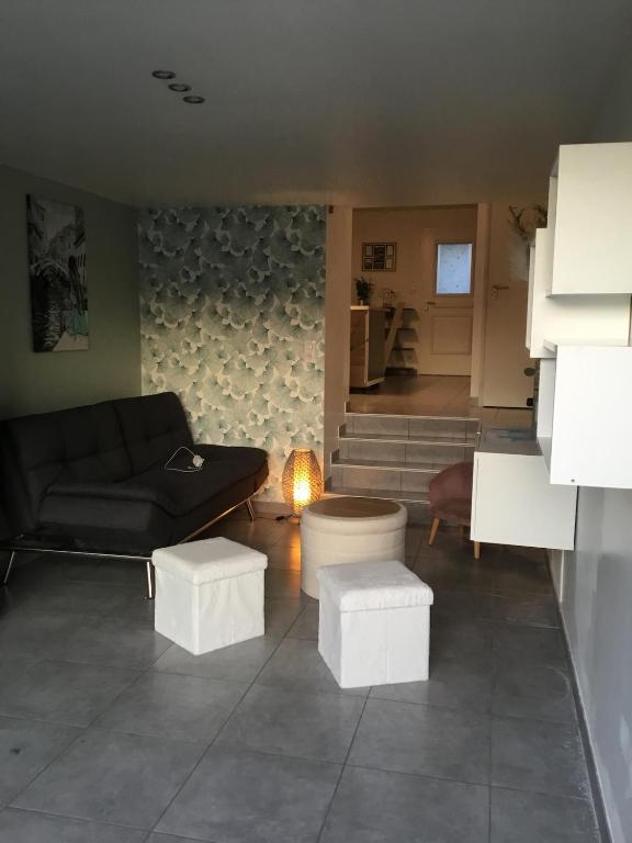 a living room with a couch and two stools at Le 7ter, maison calme piscine partagée in Saint-Laurent-sur-Sèvre