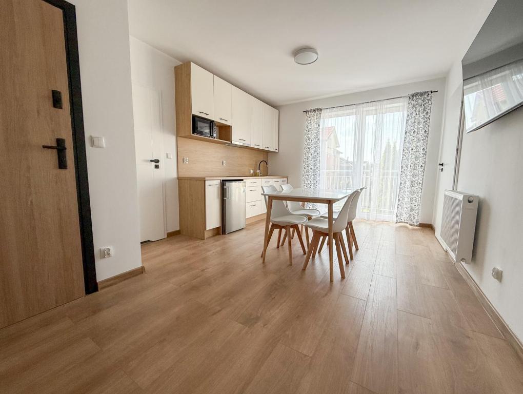 a kitchen and dining room with a table and chairs at Chatka Morska 3 Apartamenty in Karwia