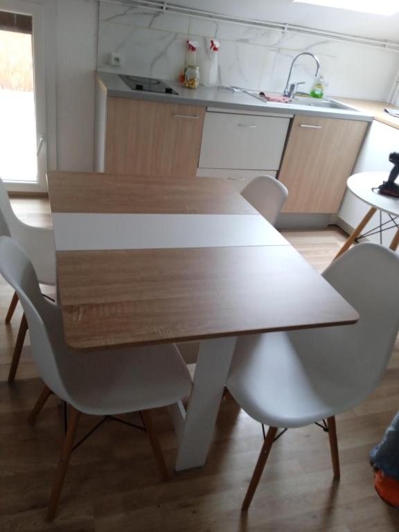 - une cuisine avec une table en bois et des chaises blanches dans l'établissement Grand T5 le canal, à Agen