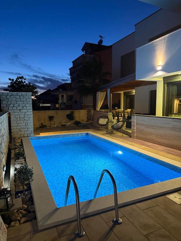 a swimming pool in front of a house at Kuća za odmor MARIA in Vodice