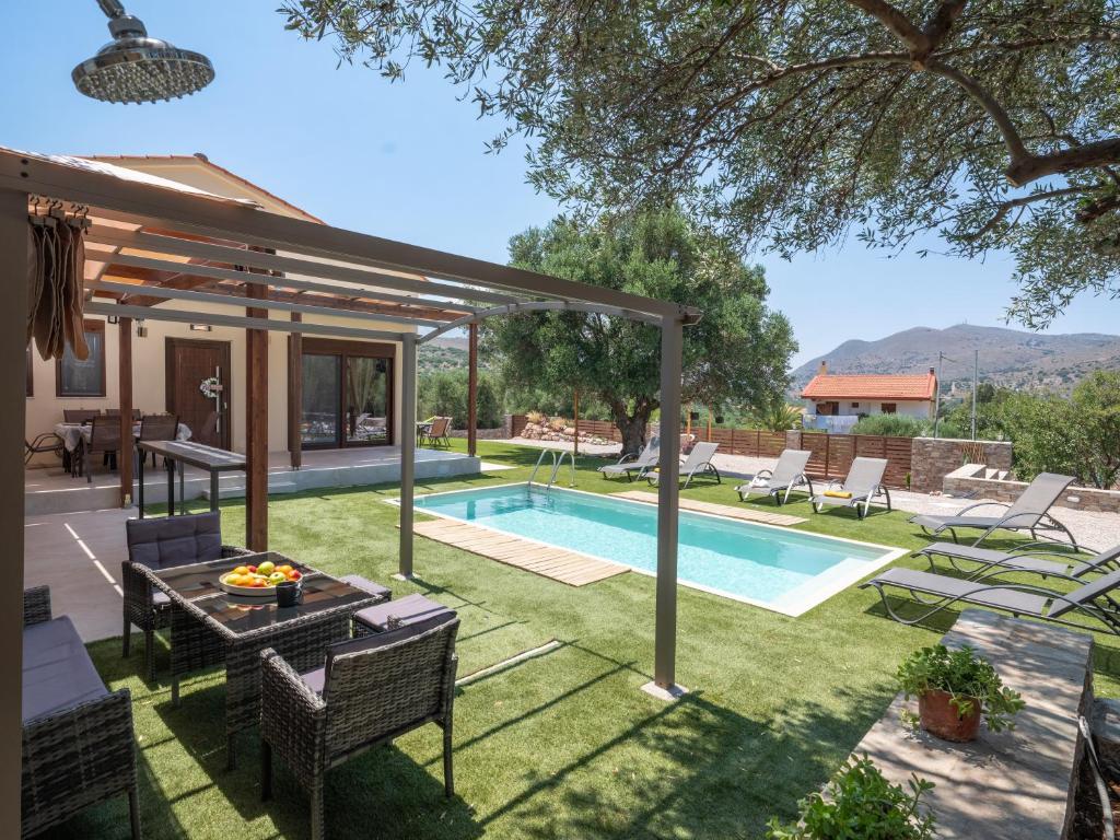 a backyard with a swimming pool and a house at Eleolithos Villa olive & pool in Fourní