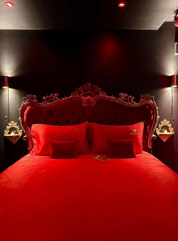 - un lit rouge avec des oreillers rouges dans une chambre noire dans l'établissement SWEET DREAMS Love room & Spa, à Villeneuve-le-Roi