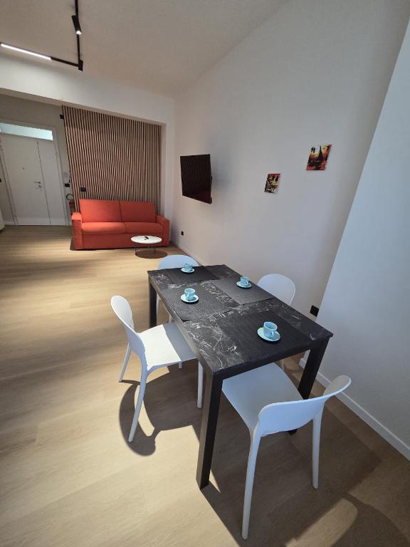 a dining room table with white chairs and a red couch at Nakupenda B&B in Cosenza