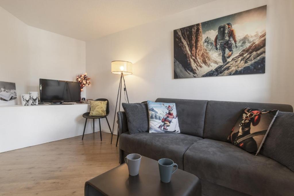 un salon avec un canapé et une télévision dans l'établissement Le Triolet - Centre-ville - Balcon avec vue, à Chamonix-Mont-Blanc