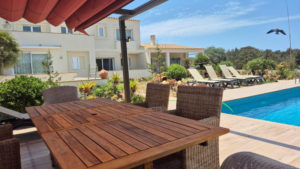 een houten tafel en stoelen op een patio met een zwembad bij Apartamentos Casa Romantica in La Savina