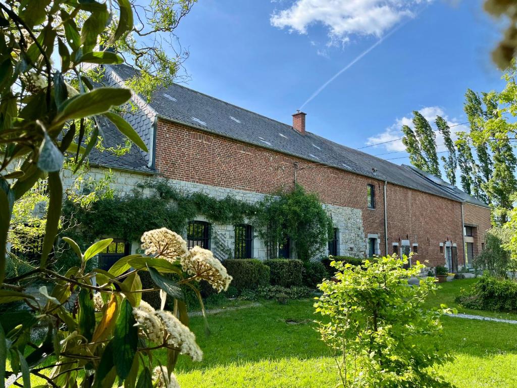 an old brick house with a green yard at La Ferme du Ravet - Gîtes aux Lacs de l'Eau d'Heure in Froid-Chapelle