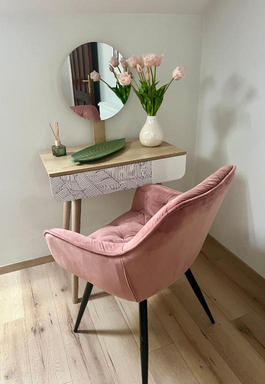 a pink chair in front of a table with a mirror at Fay-home in Odorheiu Secuiesc