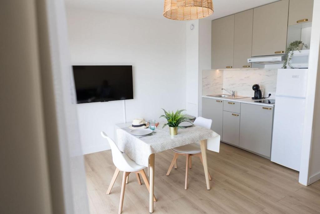 a white kitchen with a table and two chairs at Studio vue mer clim plage aéroport Nice centre commercial centre affaires Nice Arenas emplacement excellent in Saint-Laurent-du-Var