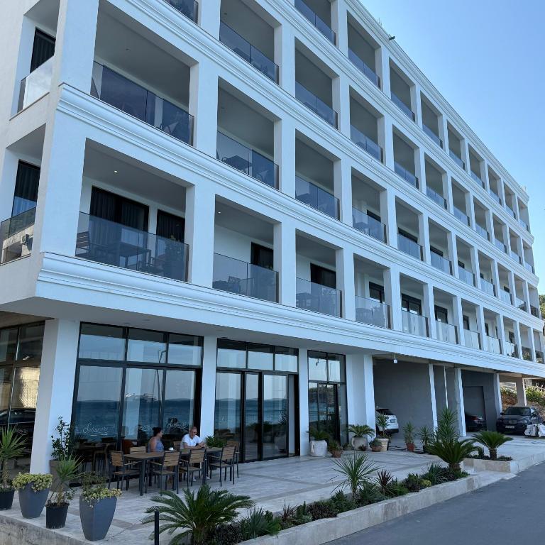 ストモレにあるHotel Sutomoreのアパートの建物の前にテーブルに人々が座っている