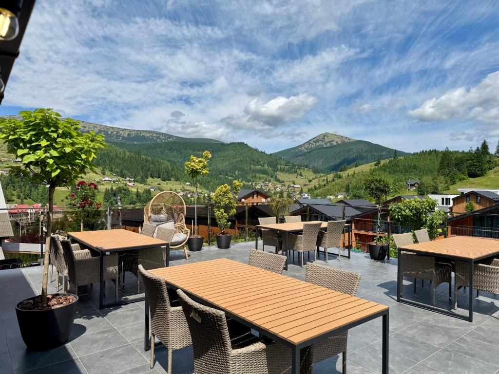 a patio with tables and chairs with mountains in the background at Chokolate house in Bukovel