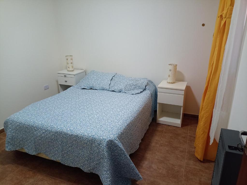 a small bedroom with a bed and two night stands at La Torre Departamento in Caleta Olivia