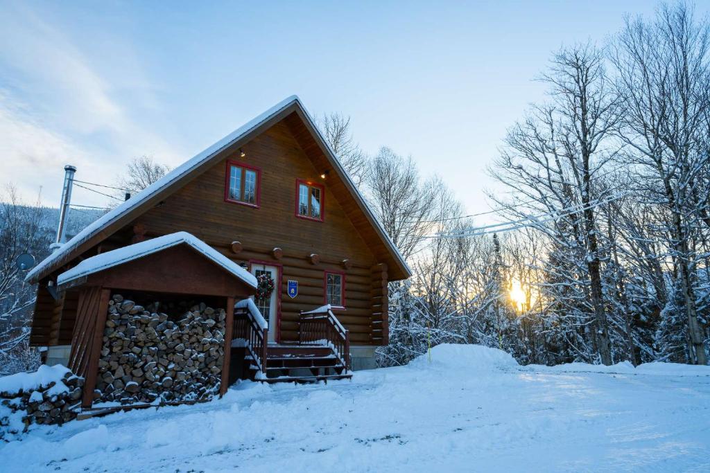 een blokhut met sneeuw op de grond naast een gebouw bij L'Antaya - SPA Mountain in Saint-Philémon