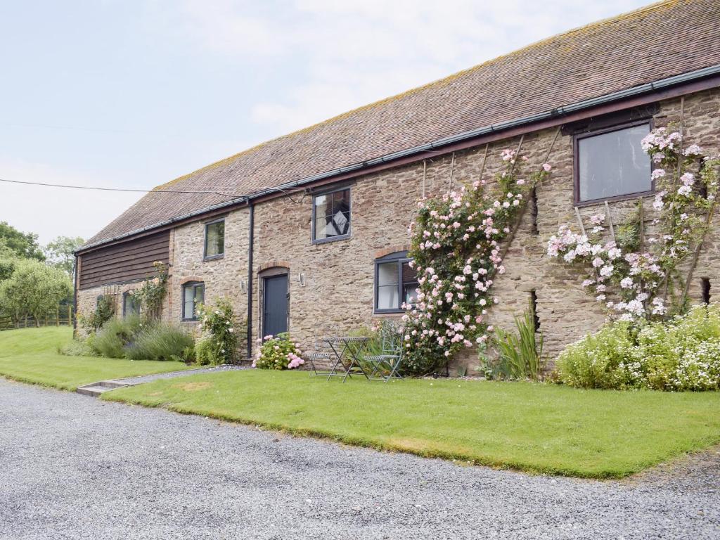 a brick building with flowers on the side of it at The Garden Room At Eudon George in Shipton