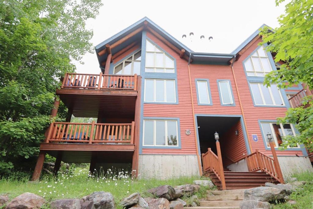 a large red house with a deck and stairs at Escapade parfaite - SPA Condo in Saint-Philémon