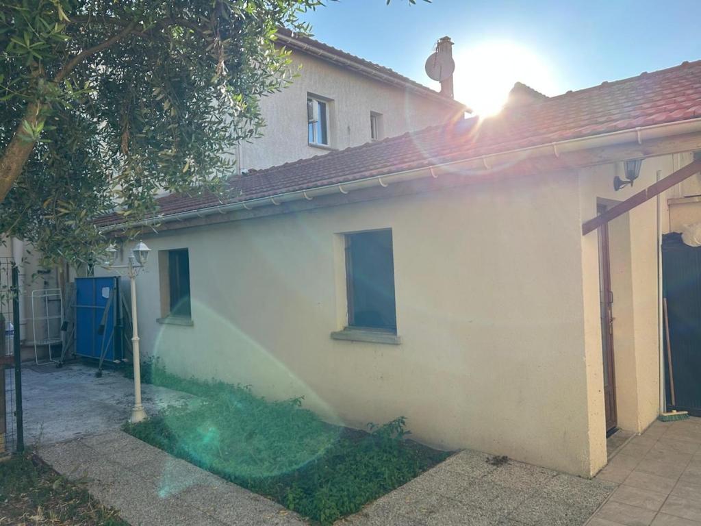 una casa blanca con una puerta azul y un árbol en Studio 5 minutes from RER A, en Nanterre