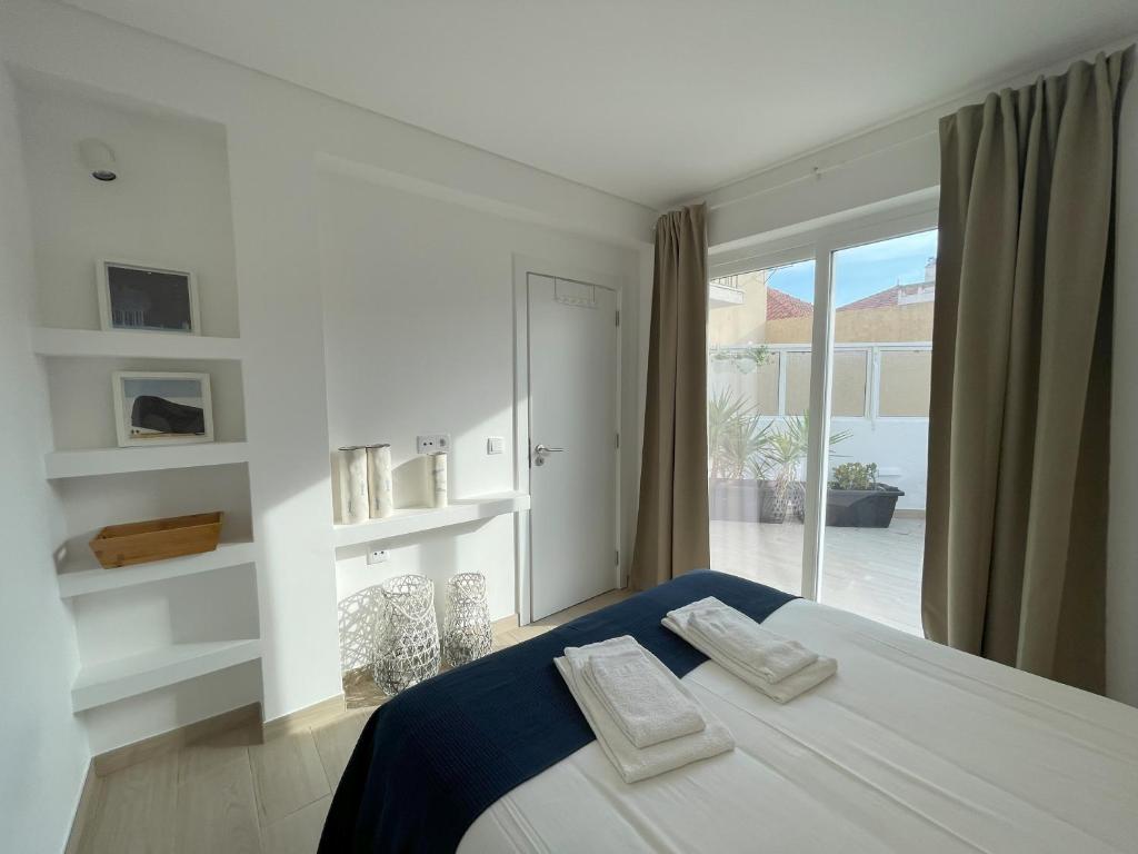 a white bedroom with a bed and a window at That Place For U - Blue House in Costa da Caparica