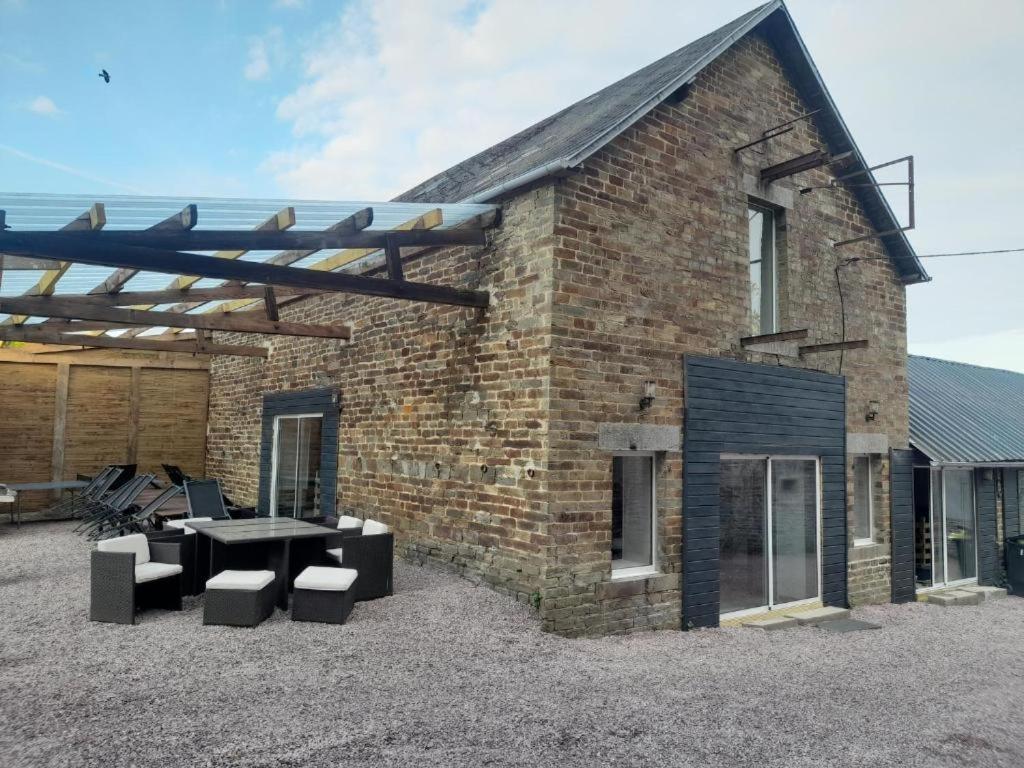 een bakstenen gebouw met een tafel en krukken buiten bij king conde in Saint-Pierre-du-Regard