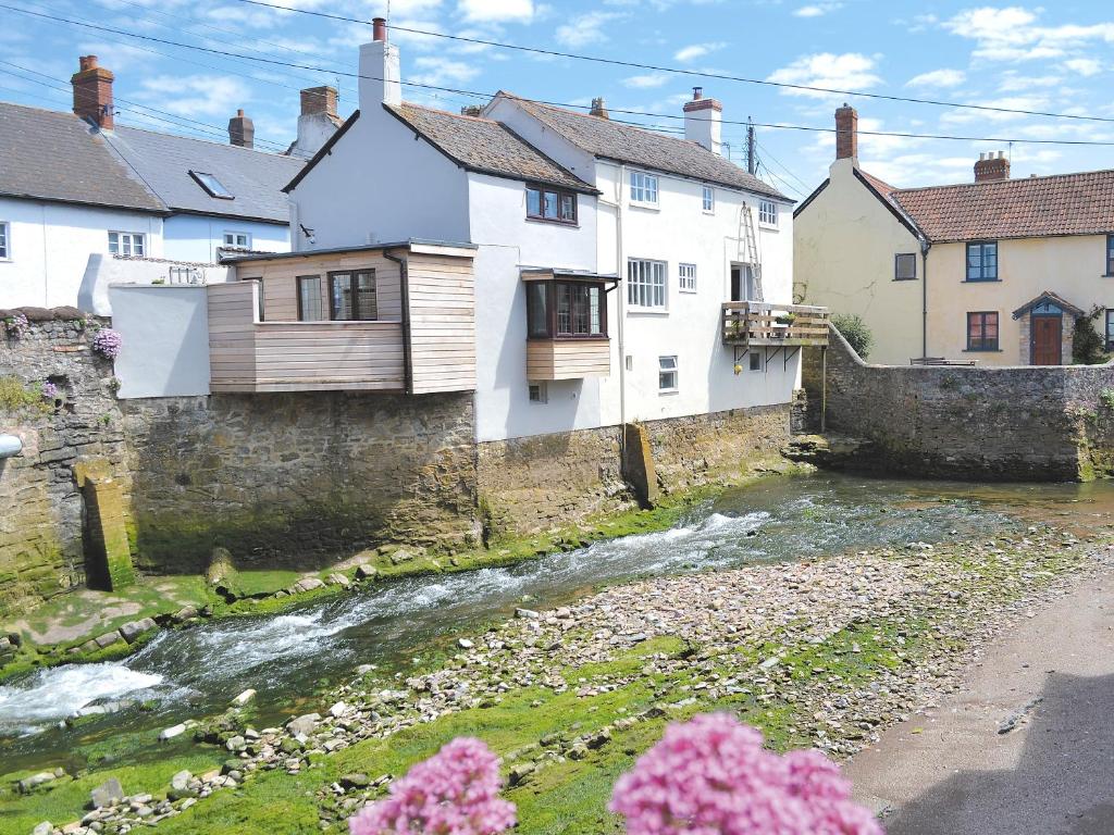 a river in a town with houses and flowers at Bridge Cottage in Watchet