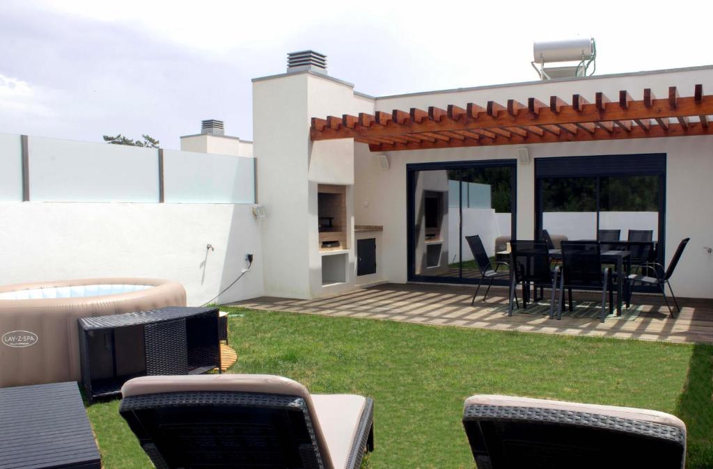 a patio with a table and chairs on the grass at Torreira Beachside House in Torreira