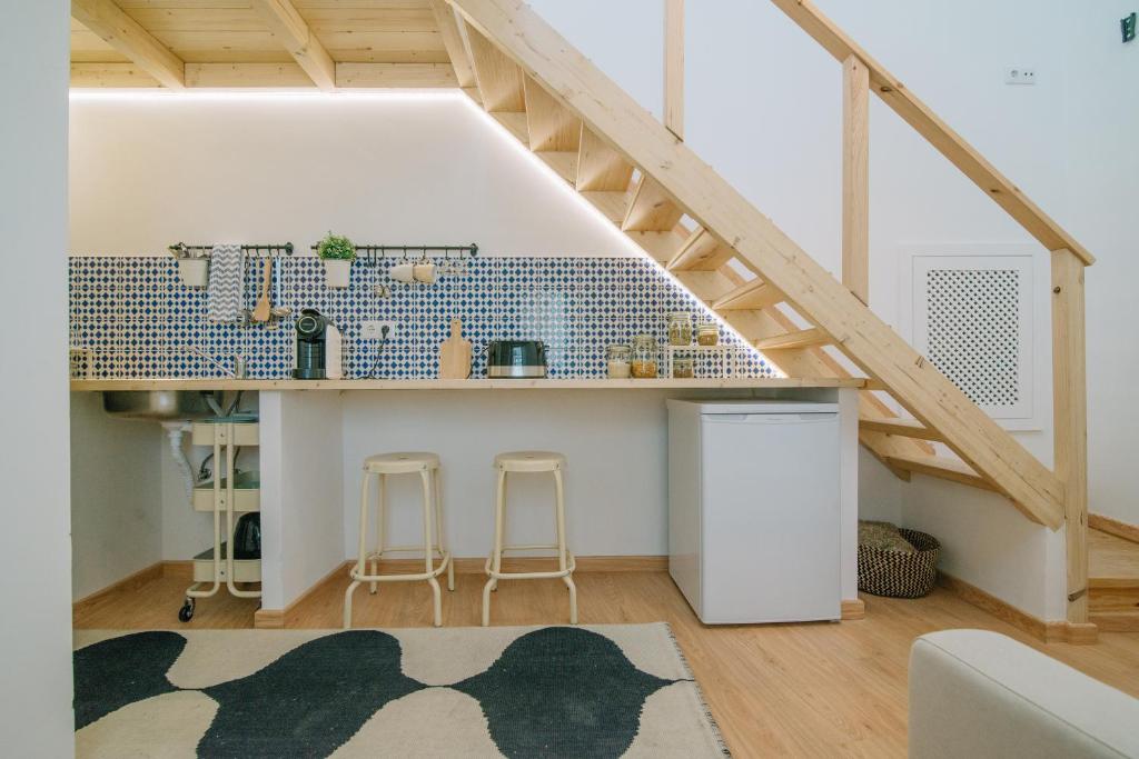 a living room with a kitchen under a staircase at Loft 11 in Olhão